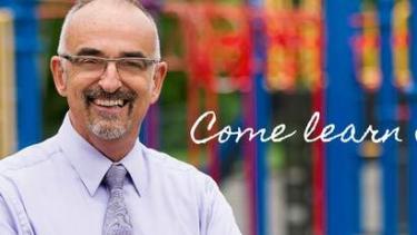 Principal standing in front of playground equipment