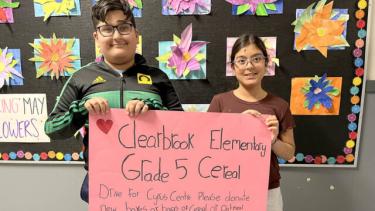 Clearbrook Cereal Drive 2023 Two elementary students stand holding a poster about the Cereal Drive