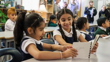 2023 King + ASIA Storytelling project two female elementary students sitting at desk looking at books made for them