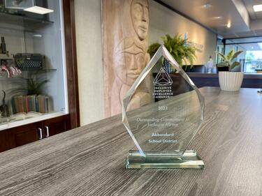 Clear glass award sits on table with front reception of district building in background