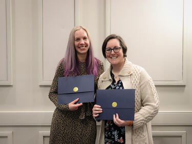 Two female recipients of the ABC program pose together with certificates
