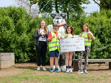 Student holding a large cheq with Husky mascot and local SPCA representative
