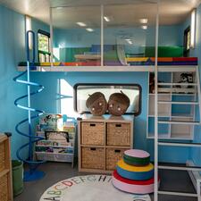 Inside an RV that has been transformed into a early learning play and reading nook for children.
