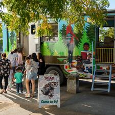 Group of kids and adults walking up to an RV that has been transformed into a play space.