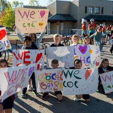 Group of young students holding up signs of appreciation for Tour de Valley riders.
