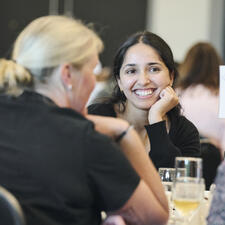 Smiling woman sitting at a table with her head resting on her hand